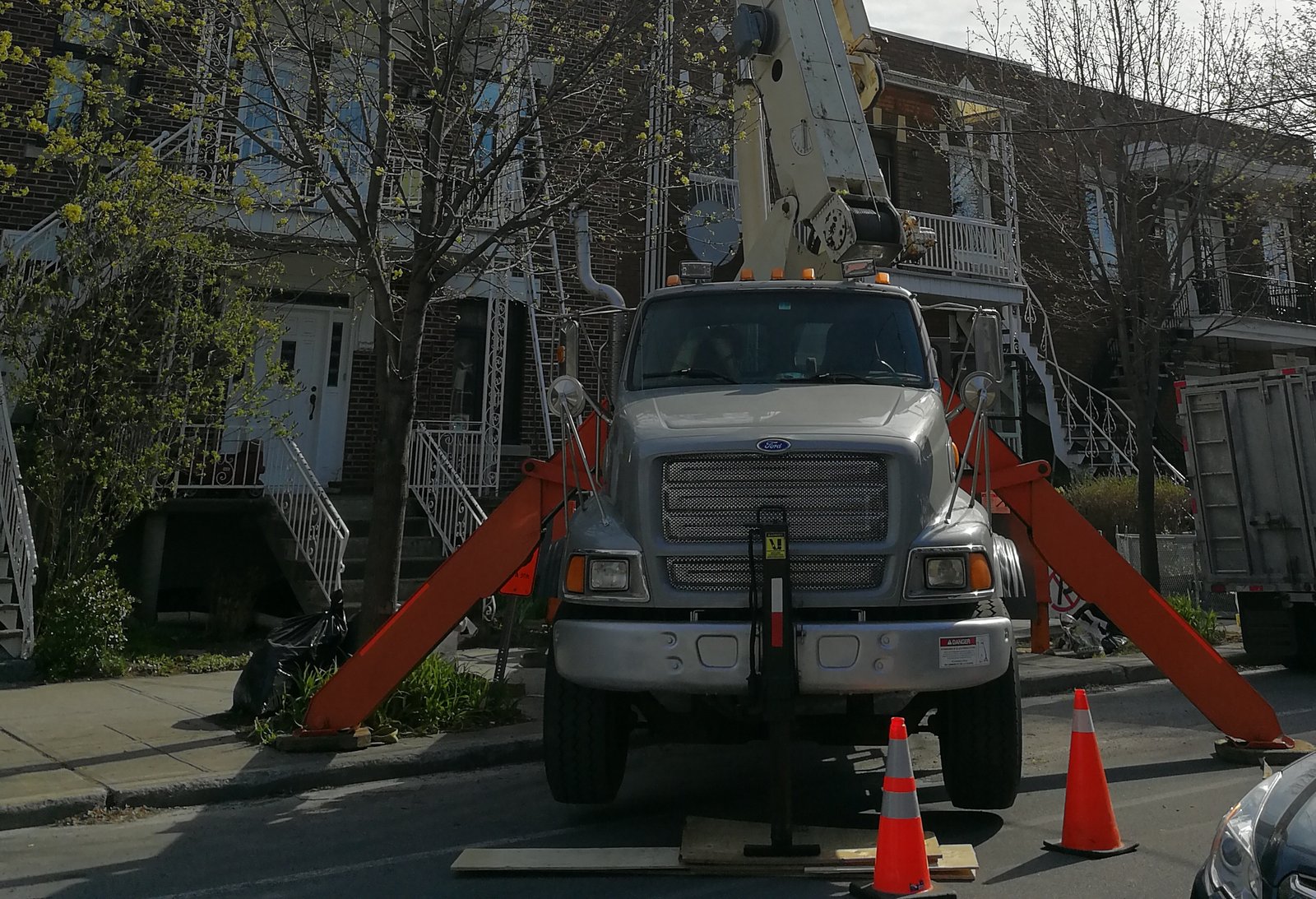 Grue mobile sur camion (camion-grue) vue de face, stabilisateurs sortis sur leurs madriers, sur une rue de Montréal