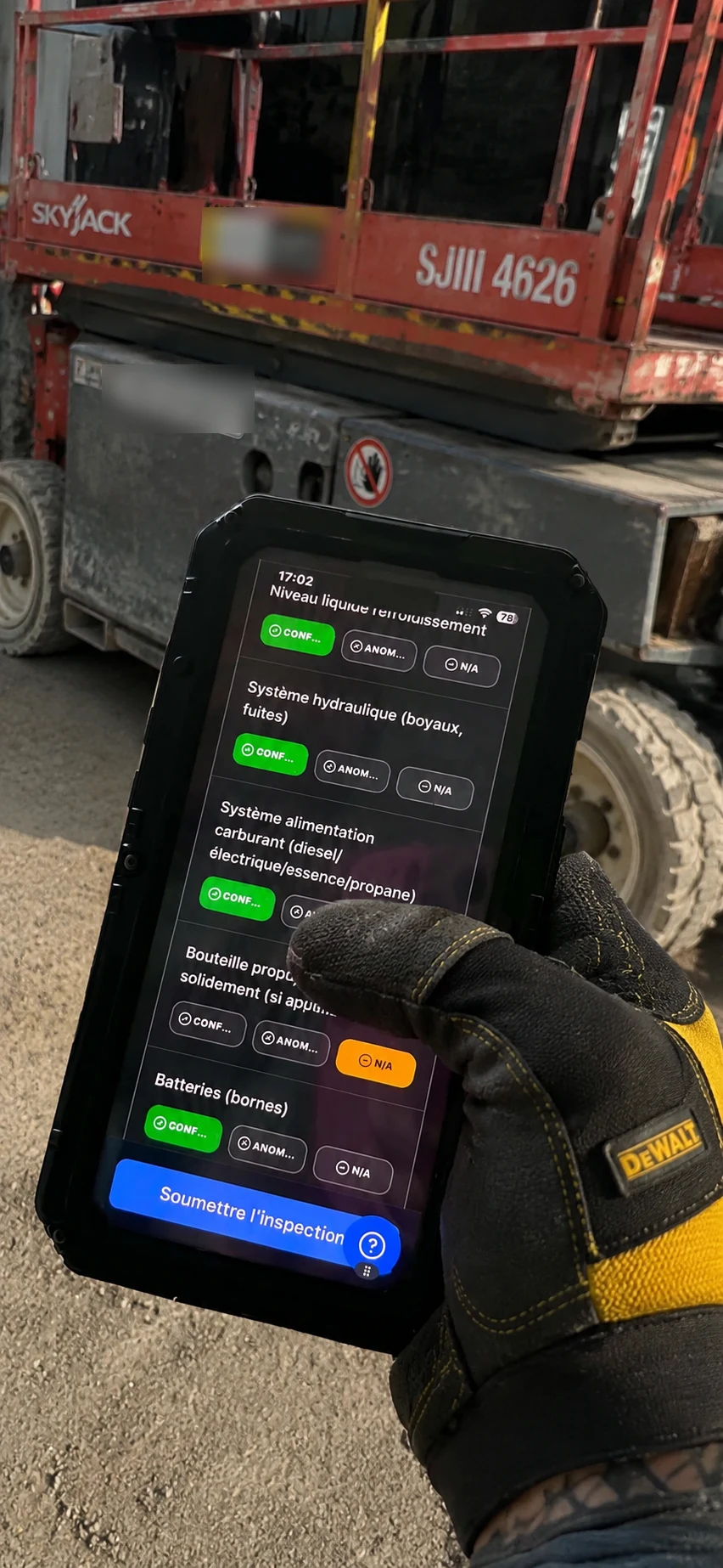 Opérateur sur un chantier remplissant la checklist d’inspection InspectoMac devant une plateforme élévatrice